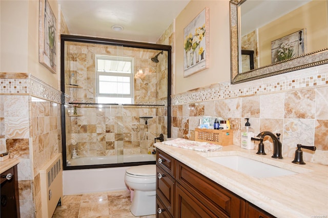 full bathroom featuring radiator, combined bath / shower with glass door, toilet, vanity, and tile walls