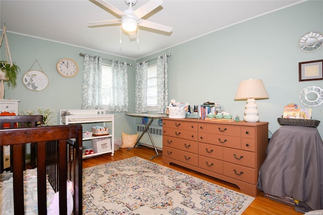 bedroom featuring ceiling fan, hardwood / wood-style floors, and radiator heating unit