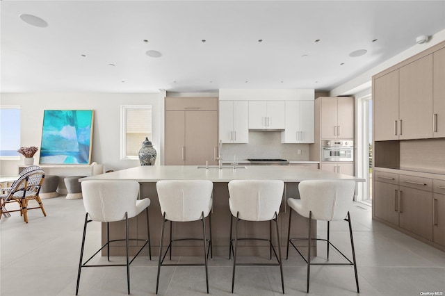 773 Dune Rd, Westhampton Beach, NY 11978 - kitchen with appliances with stainless steel finishes, backsplash, light countertops, a kitchen breakfast bar, and an island with sink