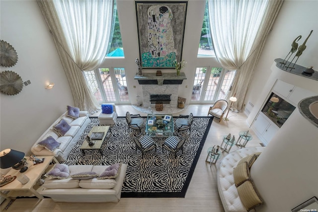 living room with french doors, a towering ceiling, and light hardwood / wood-style floors