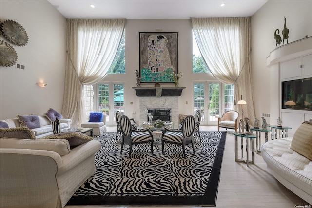 living room with a fireplace, a towering ceiling, and light hardwood / wood-style flooring