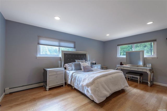 bedroom featuring baseboard heating and light hardwood / wood-style flooring