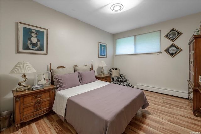 bedroom featuring light hardwood / wood-style floors and a baseboard heating unit