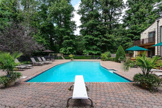 view of swimming pool with a diving board and a patio