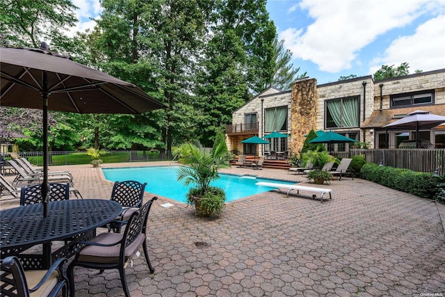 view of swimming pool featuring a diving board and a patio