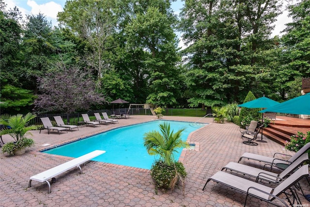 view of swimming pool featuring a patio and a diving board