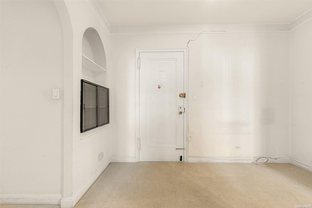 unfurnished room with ornamental molding and light carpet