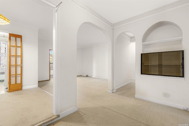 hallway with radiator, crown molding, and light colored carpet