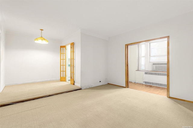 spare room featuring carpet, ornamental molding, radiator, and french doors