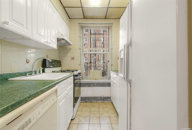 kitchen featuring a paneled ceiling, white appliances, white cabinets, light tile patterned floors, and range hood