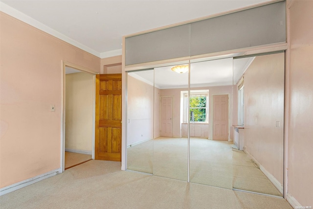 unfurnished bedroom featuring light colored carpet, ornamental molding, and a closet