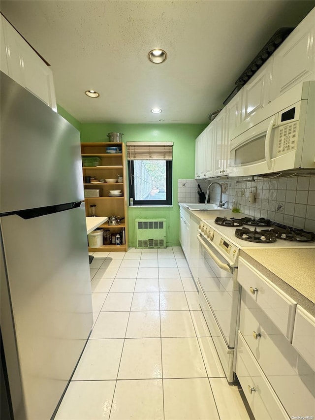 kitchen featuring decorative backsplash, white appliances, sink, white cabinetry, and light tile patterned flooring