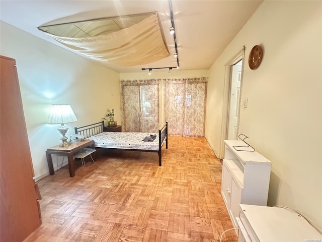 bedroom with rail lighting and light parquet flooring