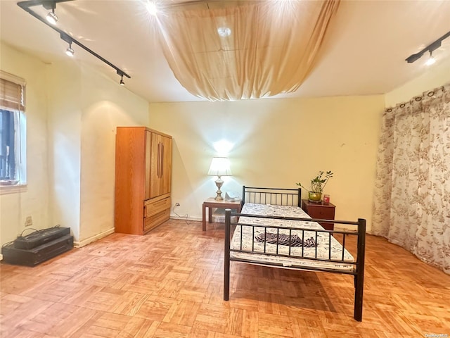 bedroom with light parquet floors and track lighting