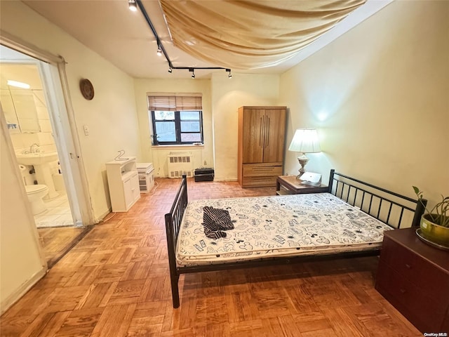 bedroom featuring connected bathroom, track lighting, radiator, and light parquet flooring