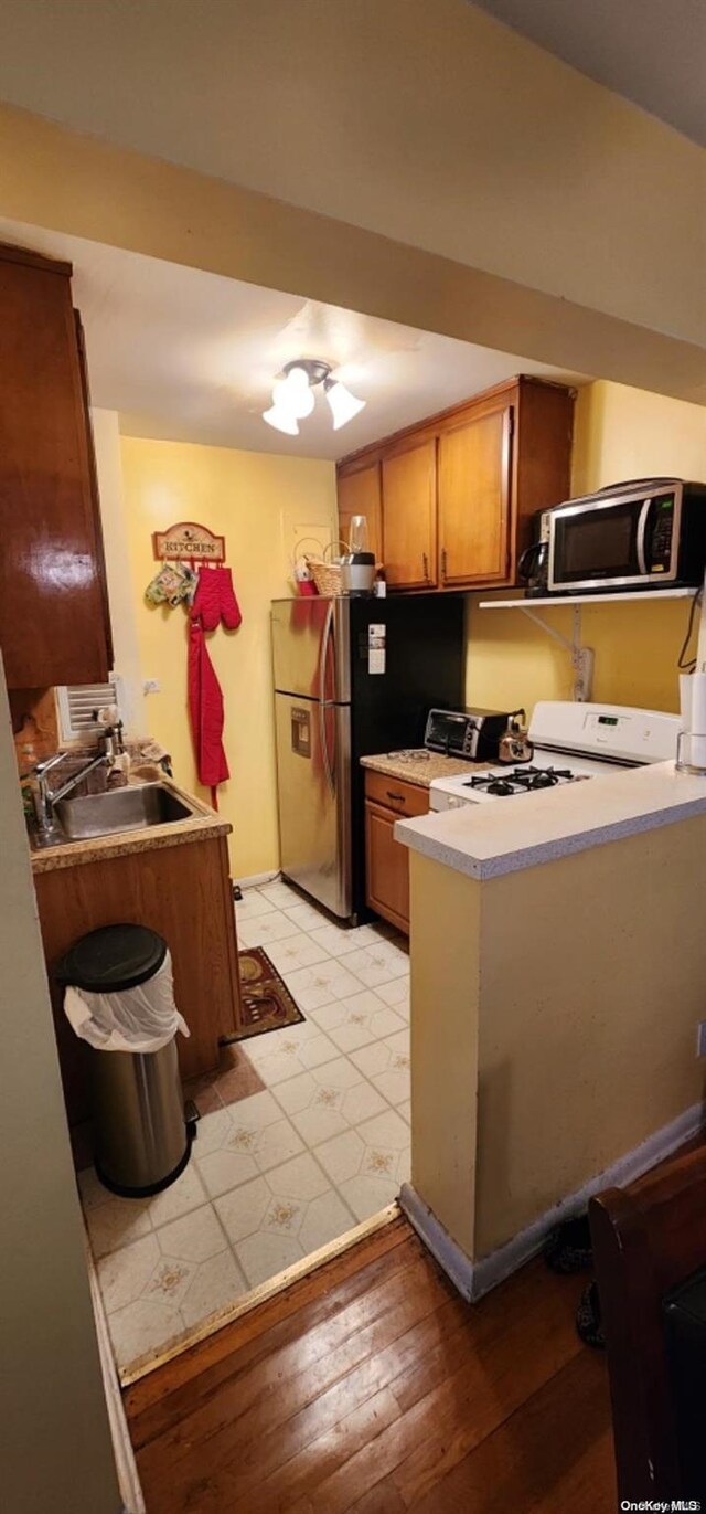 kitchen with light hardwood / wood-style floors, kitchen peninsula, sink, and appliances with stainless steel finishes