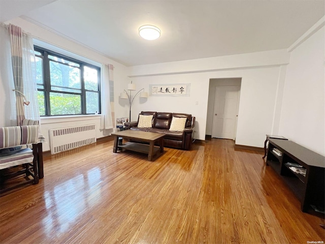 living room with radiator heating unit, hardwood / wood-style flooring, and crown molding