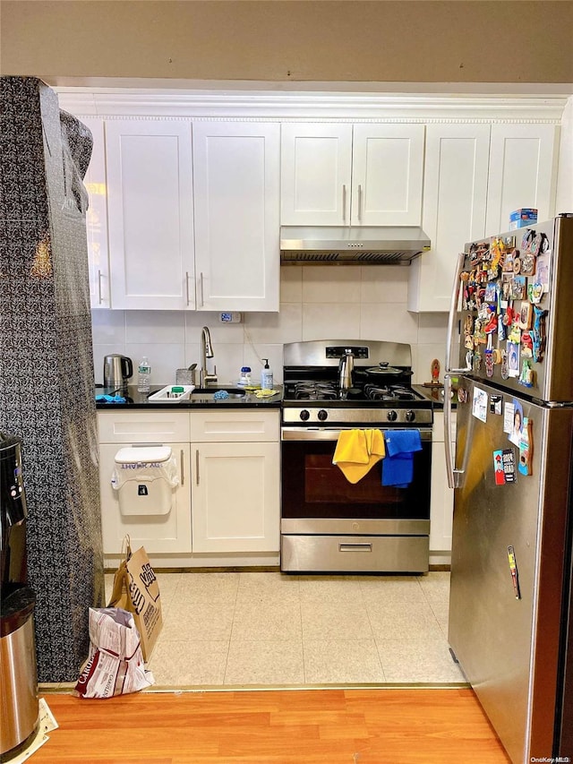 kitchen with tasteful backsplash, white cabinetry, stainless steel appliances, and light wood-type flooring