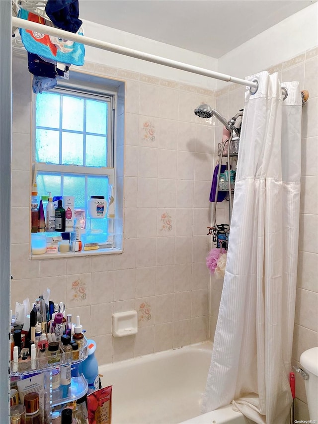 bathroom with shower / bath combination with curtain, toilet, and tile walls