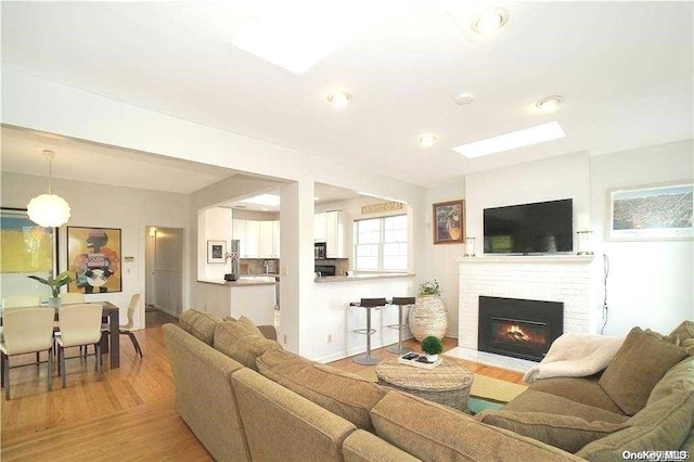 living room with light hardwood / wood-style floors and a brick fireplace