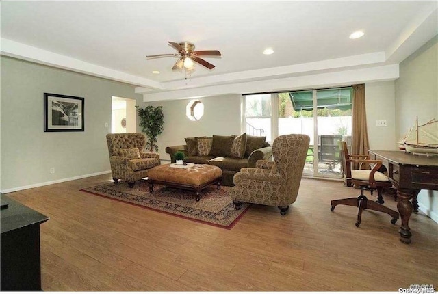 living room featuring a tray ceiling, ceiling fan, and hardwood / wood-style floors