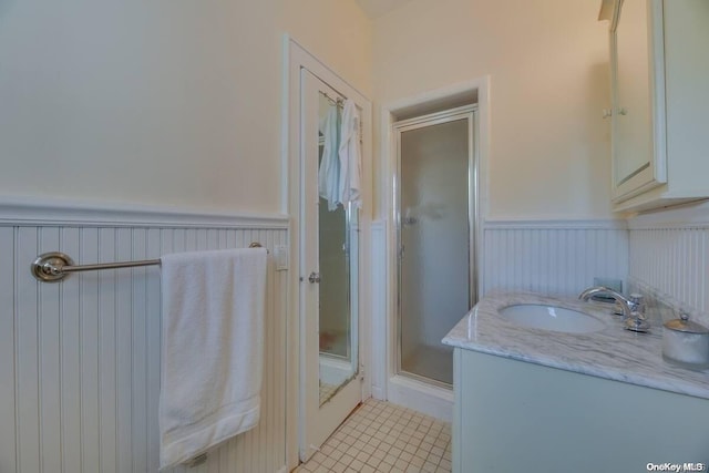 bathroom with tile patterned flooring, vanity, and walk in shower