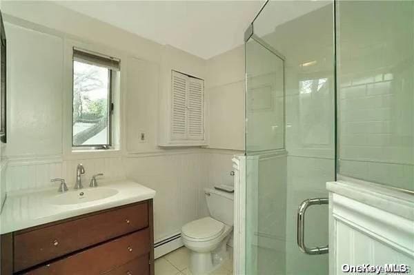 bathroom featuring vanity, a shower with door, a baseboard radiator, tile walls, and toilet