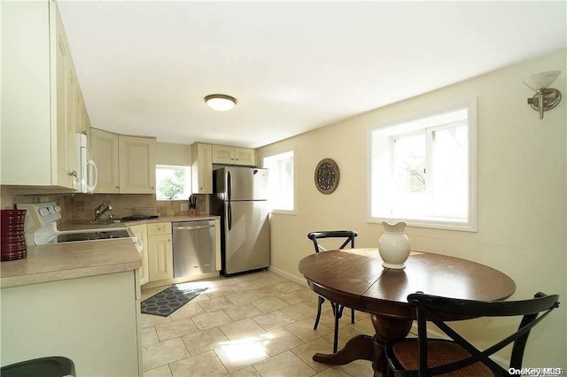 215 Roosevelt Blvd, Long Beach, NY 11561 - kitchen featuring appliances with stainless steel finishes, backsplash, light countertops, cream cabinets, and light tile patterned flooring
