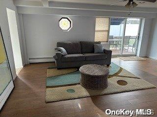 215 Roosevelt Blvd, Long Beach, NY 11561 - living room with ceiling fan, wood finished floors, a baseboard radiator, and baseboards