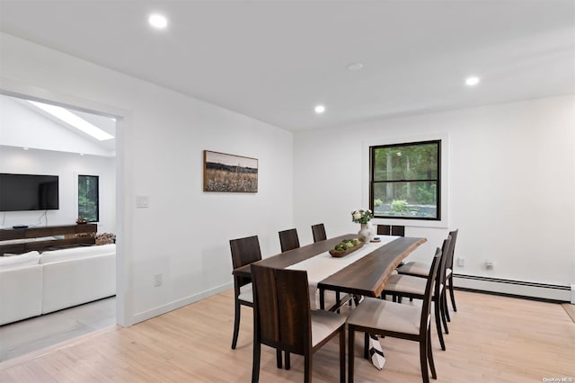 dining space featuring baseboard heating, light hardwood / wood-style flooring, and lofted ceiling