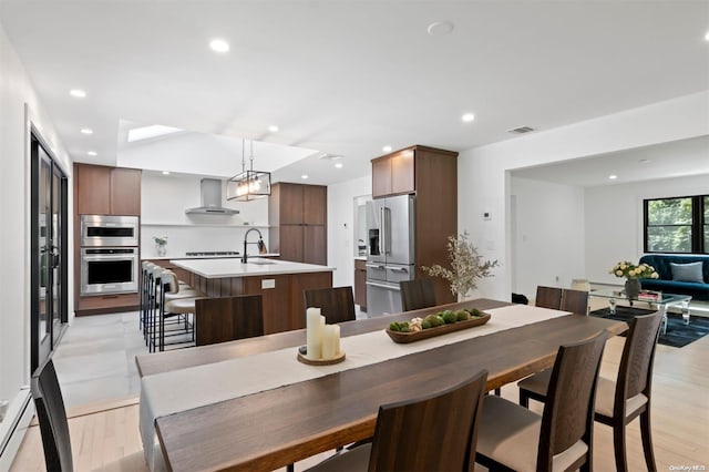 dining area with light hardwood / wood-style flooring, baseboard heating, and sink