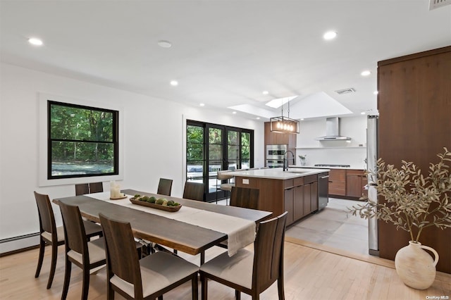 dining space featuring a skylight, light hardwood / wood-style floors, and sink