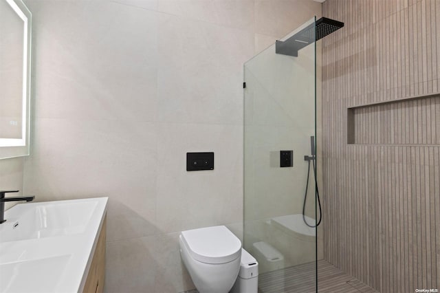 bathroom featuring vanity, toilet, tile walls, and walk in shower