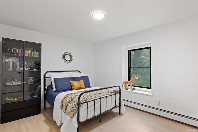 bedroom with hardwood / wood-style flooring and a baseboard heating unit