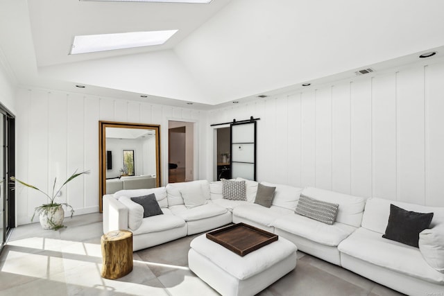 living area featuring a skylight, a barn door, visible vents, and high vaulted ceiling