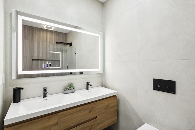 bathroom featuring double vanity, a sink, and tile walls