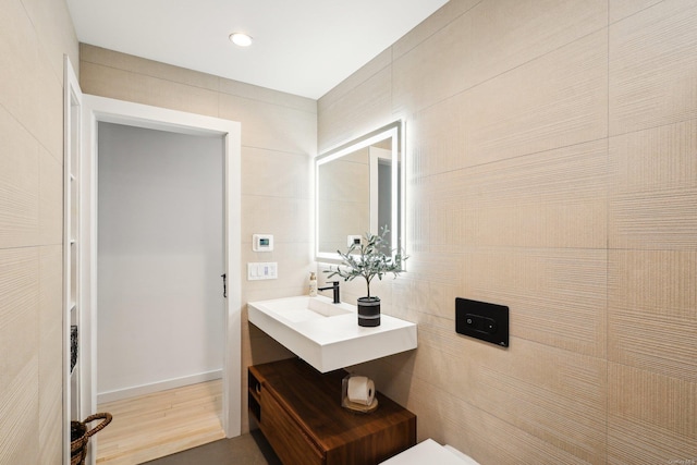 bathroom featuring recessed lighting, a sink, and wood finished floors