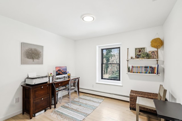 office featuring a baseboard radiator, baseboards, and light wood-style flooring