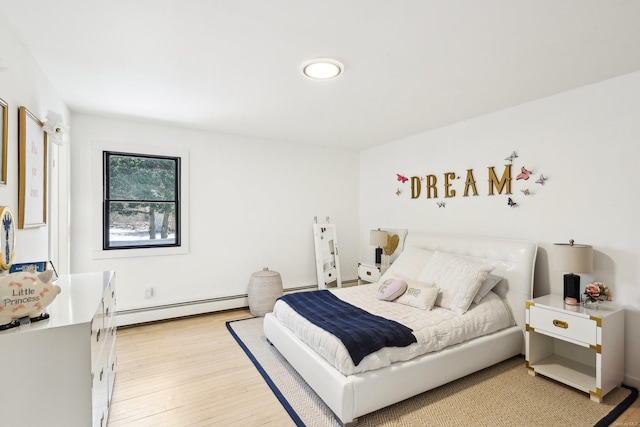 bedroom with light wood-style flooring and a baseboard heating unit