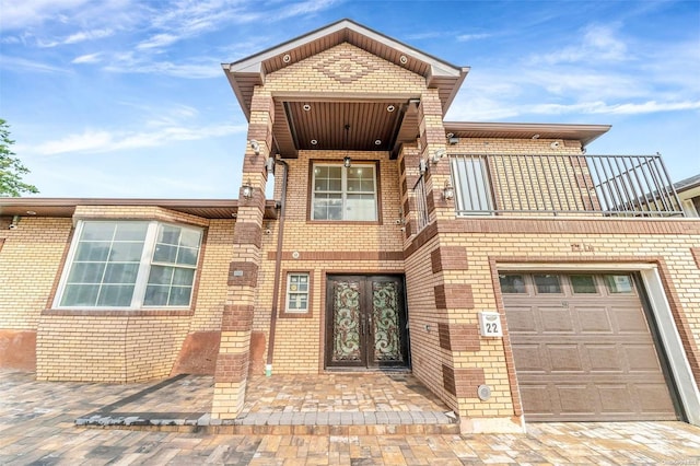 view of front of property with french doors, a balcony, and a garage