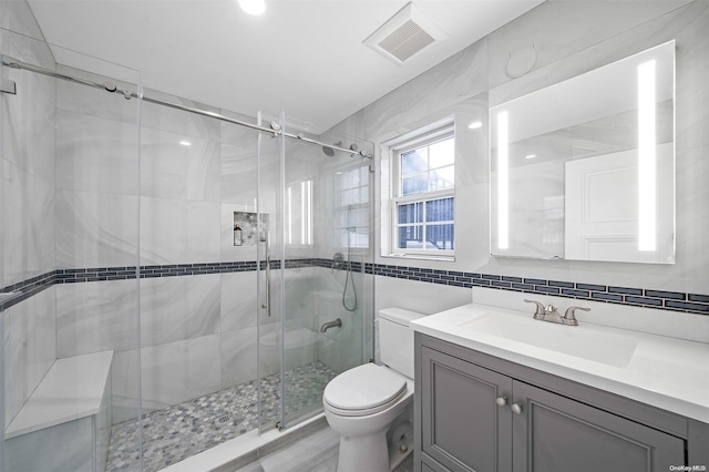 bathroom featuring vanity, a shower with shower door, tile walls, and toilet