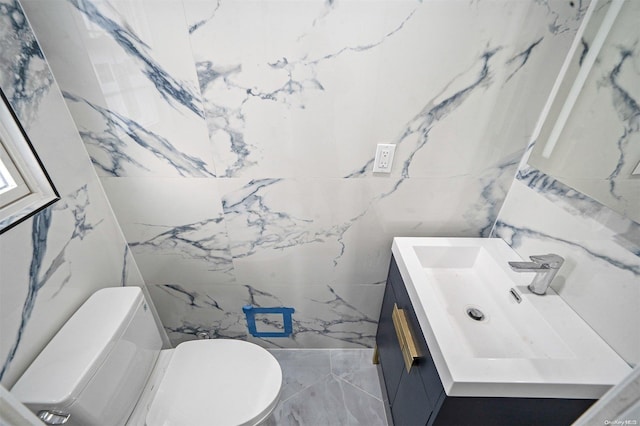 bathroom with vanity, tile walls, and toilet