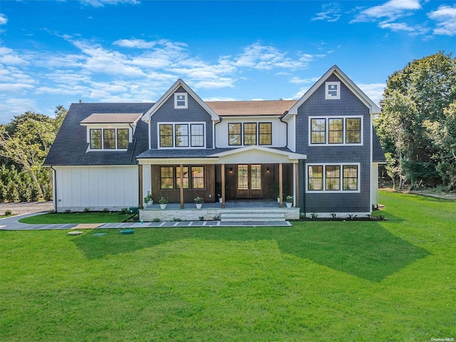 rear view of house featuring a lawn and covered porch