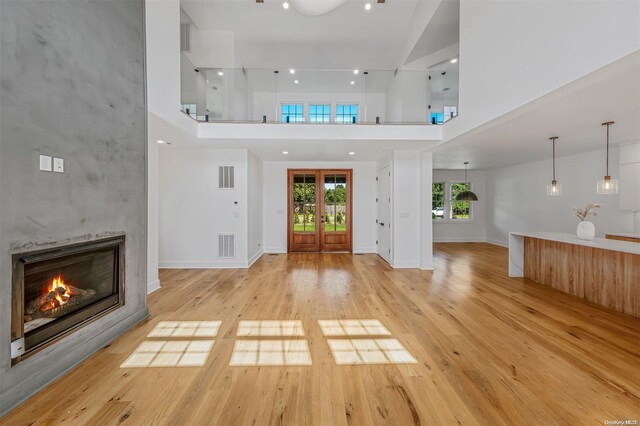 2060 Shipyard Ln, East Marion, NY 11939 - foyer with a towering ceiling, a tiled fireplace, light wood-type flooring, french doors, and baseboards