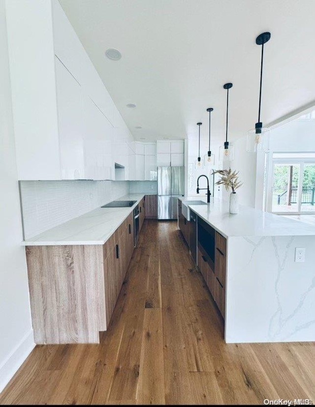 kitchen with decorative backsplash, appliances with stainless steel finishes, hanging light fixtures, and dark wood-type flooring