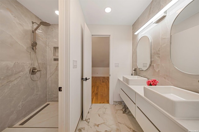 bathroom featuring vanity, a tile shower, and wood-type flooring