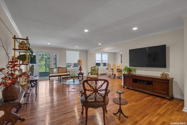 living room featuring a textured ceiling, light wood-type flooring, crown molding, and a wealth of natural light