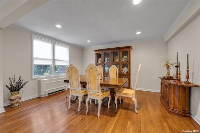 dining room with a textured ceiling, light hardwood / wood-style flooring, and crown molding