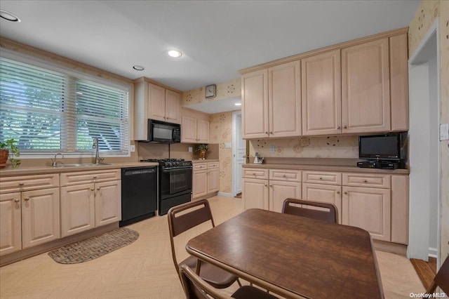 kitchen with tasteful backsplash, sink, light parquet floors, and black appliances