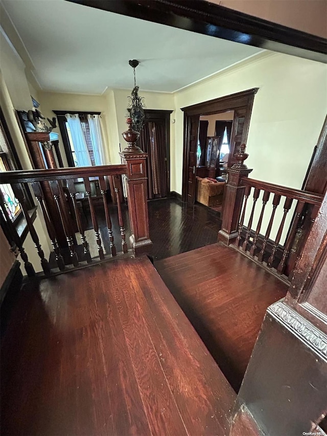 staircase featuring crown molding, wood-type flooring, and a notable chandelier